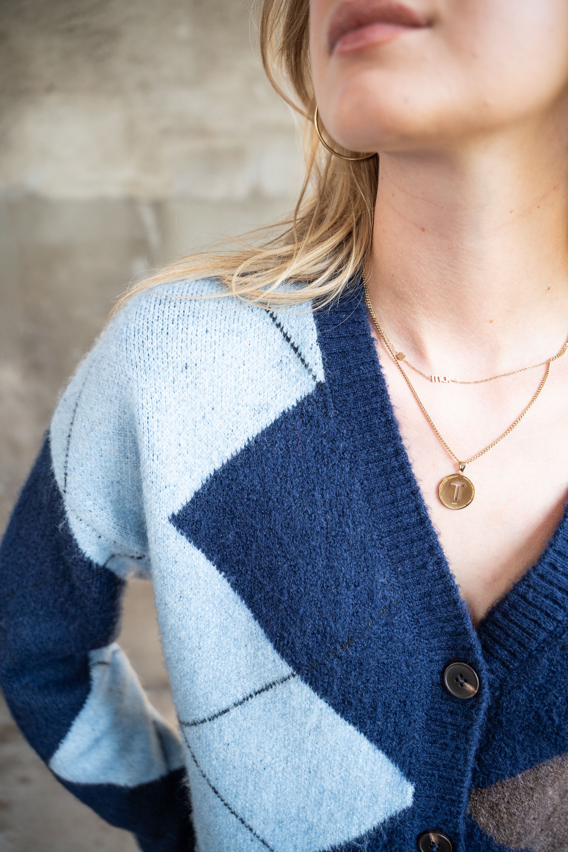 Close-up van een vrouw met een blauw-wit gestreept vest en een gouden ketting.