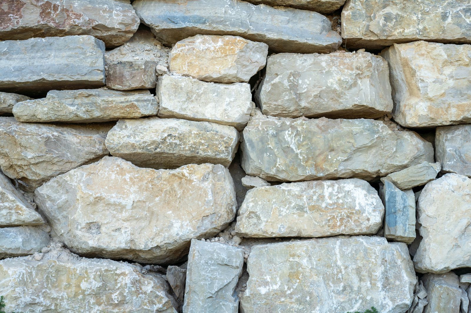 Stacked pale stone wall with irregular rough stones and visible mortar gaps