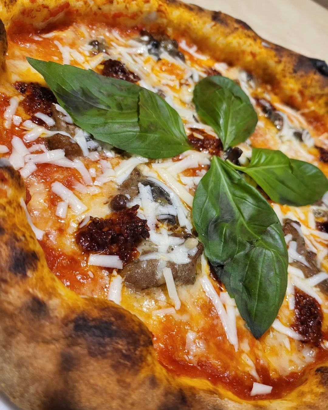 Pizza Margherita con foglie di basilico fresco, formaggio fuso e crosta leggermente bruciacchiata.