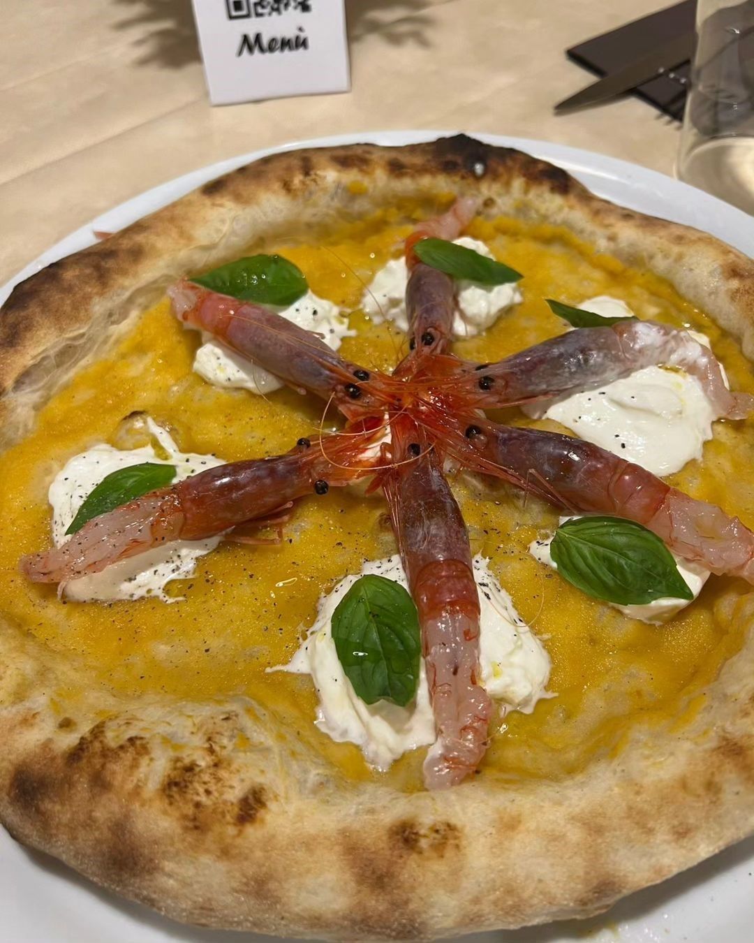 Pizza con salsa all'arancia, mozzarella, basilico e sottili fette di salumi su un piatto