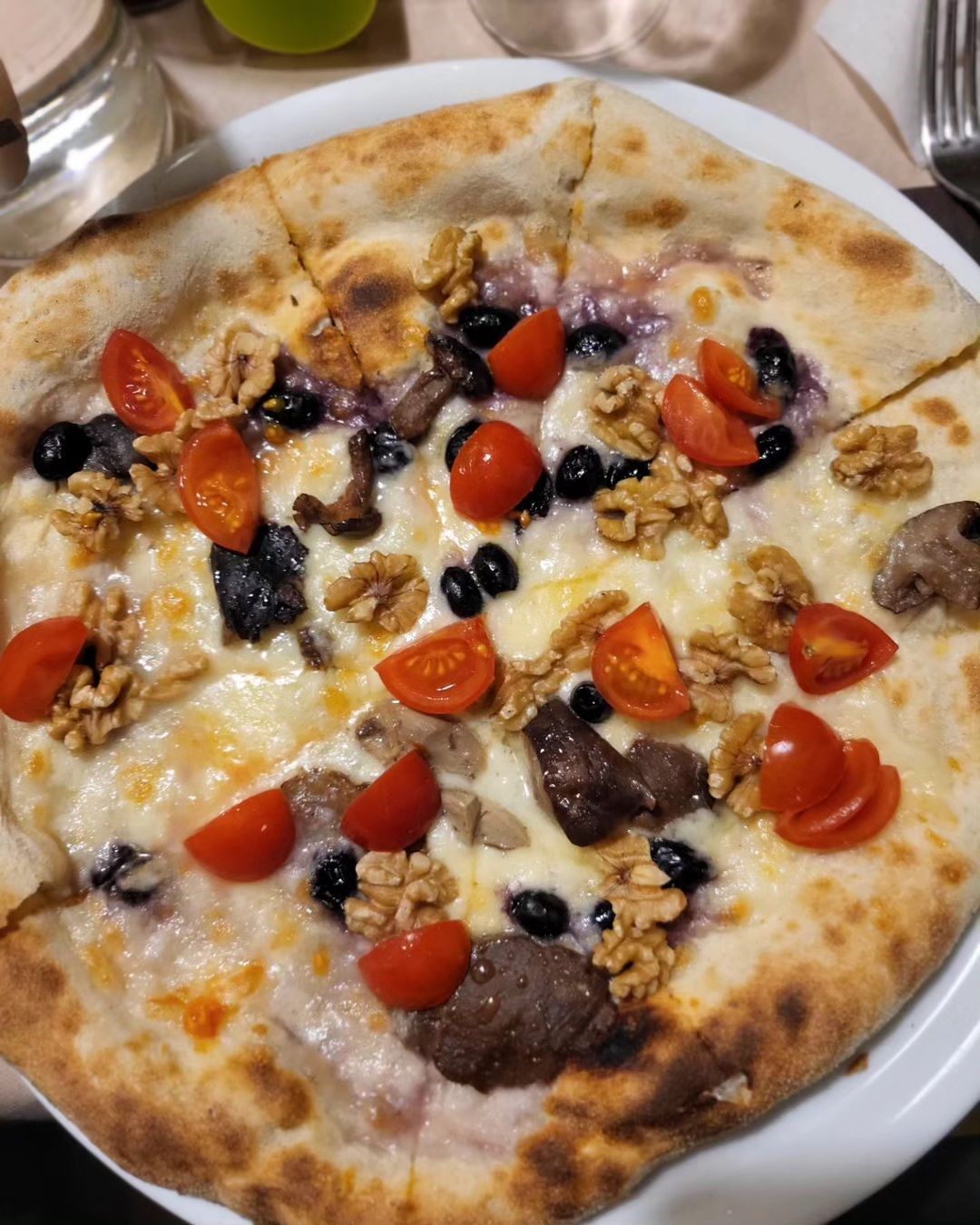 Pizza bianca con pomodorini e funghi su un piatto