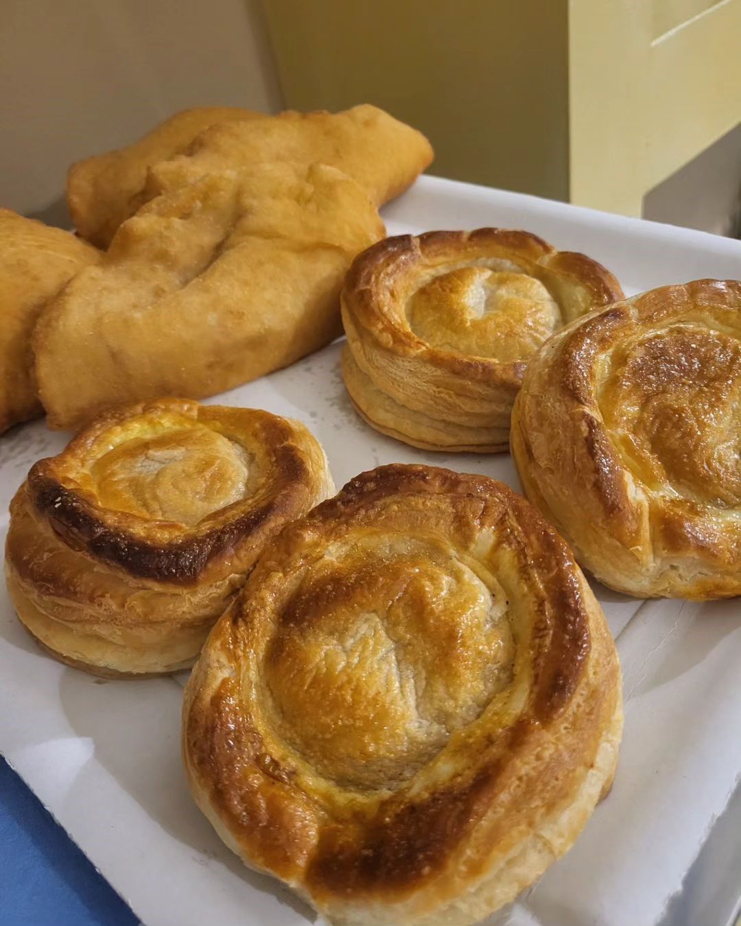 Piatto con pasticcini dorati e una sfoglia fritta su carta bianca