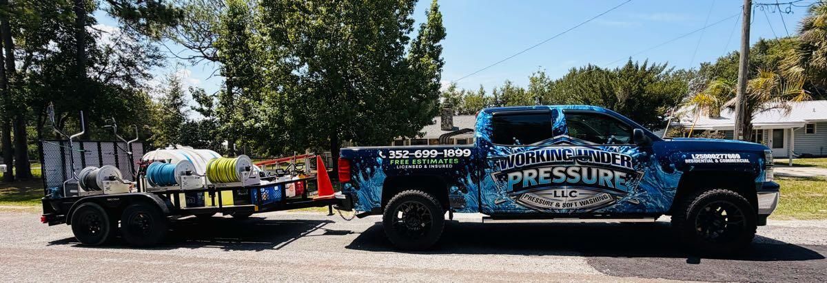 Black truck with “TIRE PRESSURE” branding parked by a roadside with utility trucks and trees nearby