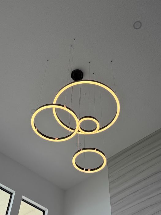 Three glowing ring pendant lights hanging from a white ceiling in a modern room