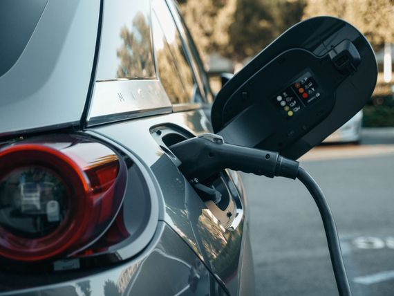 Electric car charging at a curbside station, close-up of charging plug and rear taillight