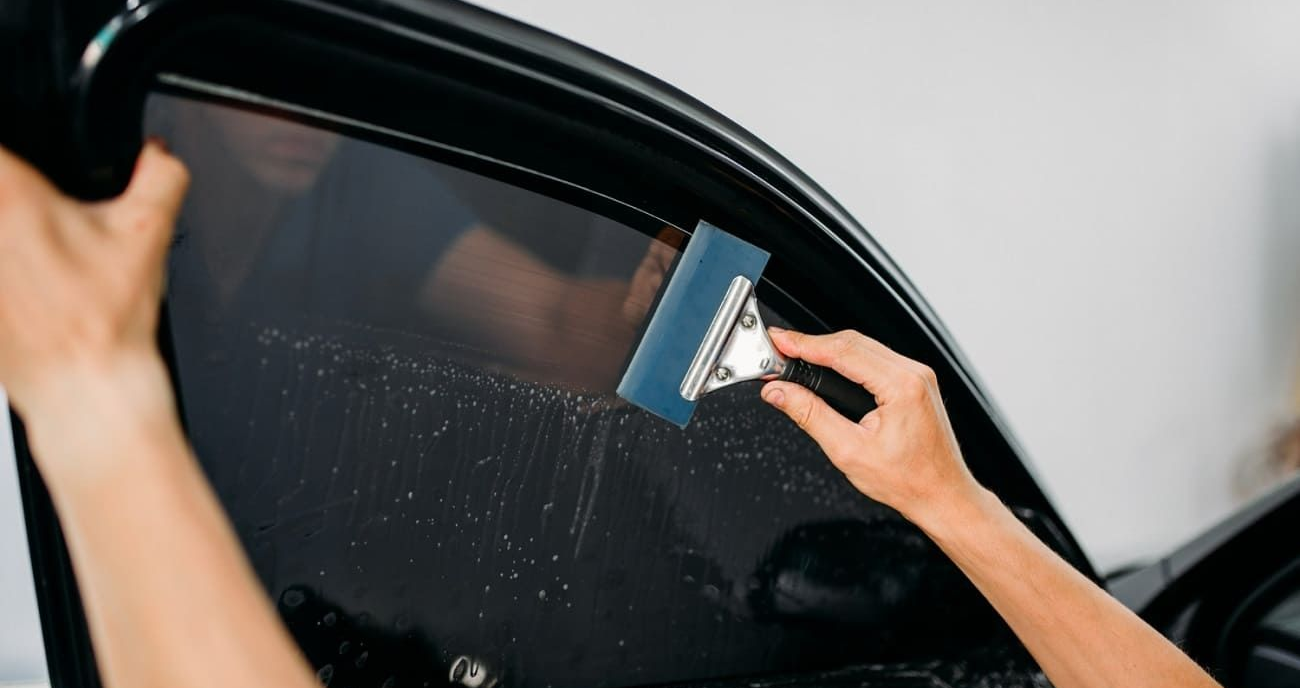 Professional technician installing window tint film using a squeegee