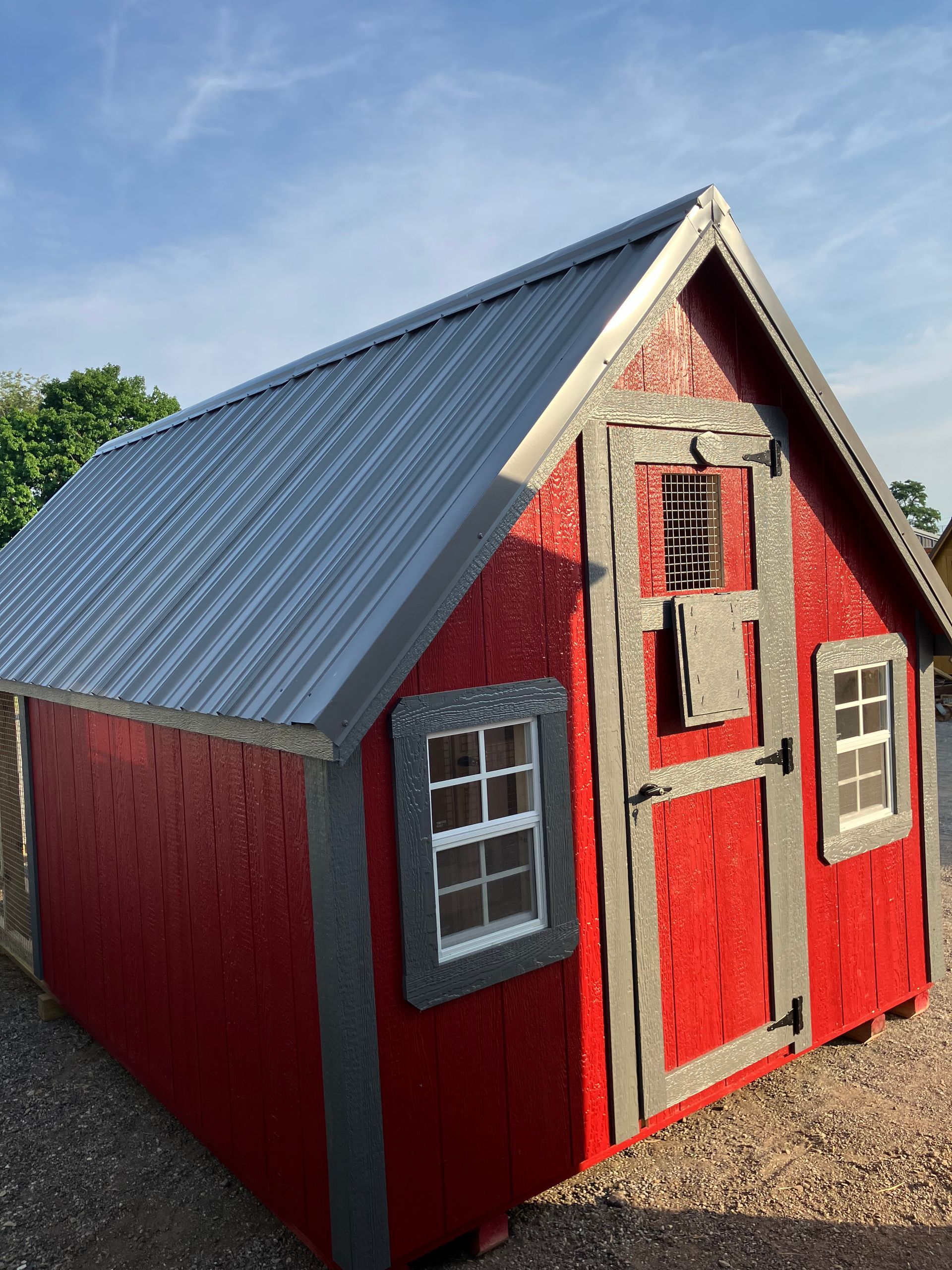 Red shed with gray trim and metal roof, two windows, and door.
