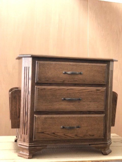 Wooden nightstand with three drawers and magazine racks on either side.