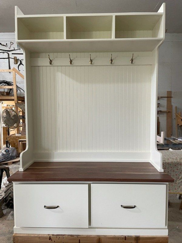 White and brown wooden storage bench with drawers, hooks, and overhead shelves.