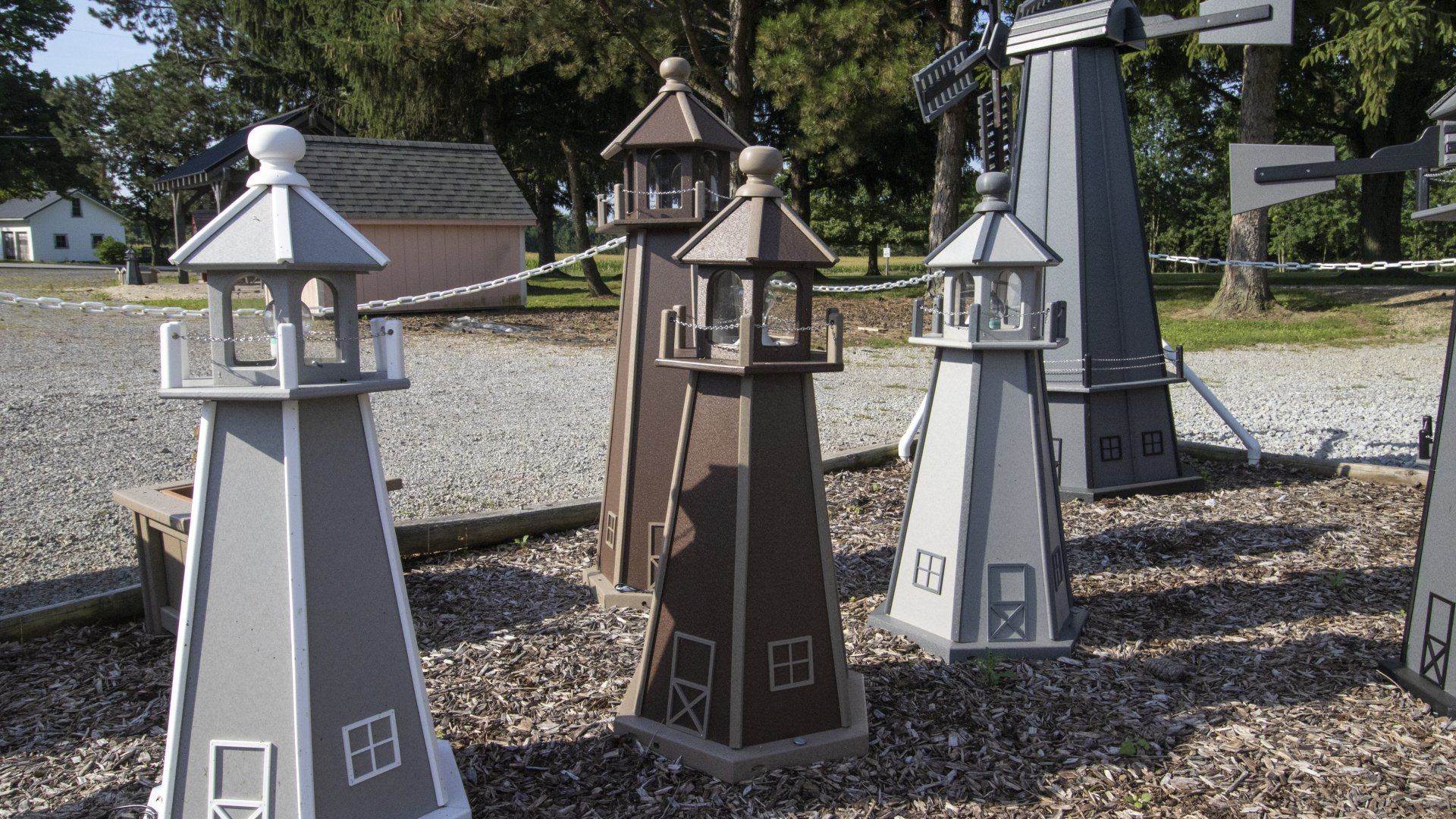 Wooden decorative lighthouses of various colors in an outdoor setting.