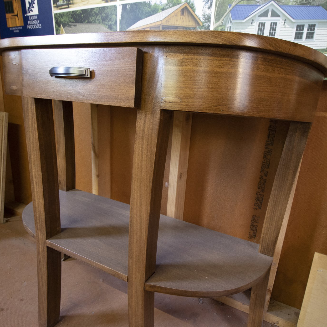Wooden console table with drawer and shelf, stained brown, in a workshop setting.