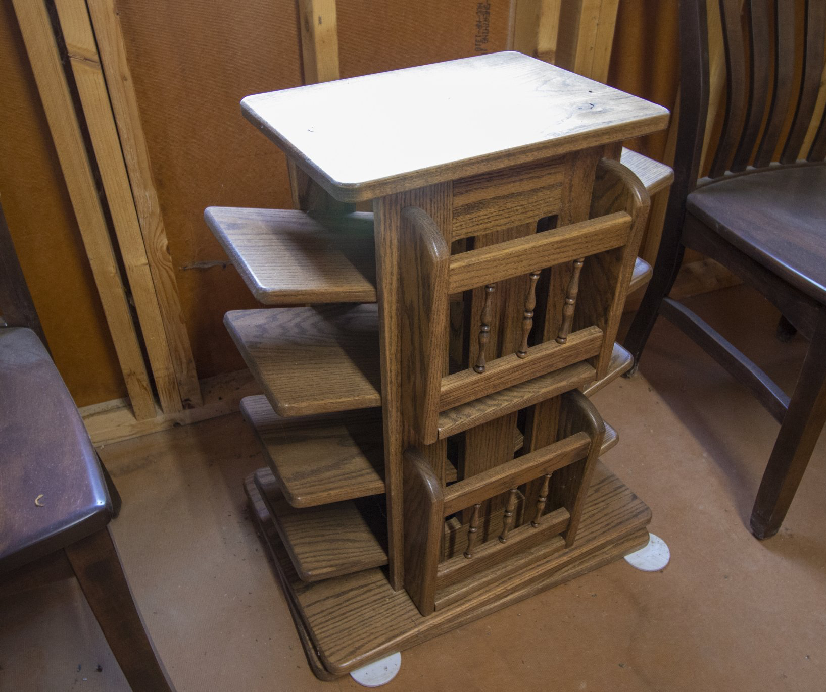 Oak wooden magazine stand with several shelves and a small top surface, indoors.