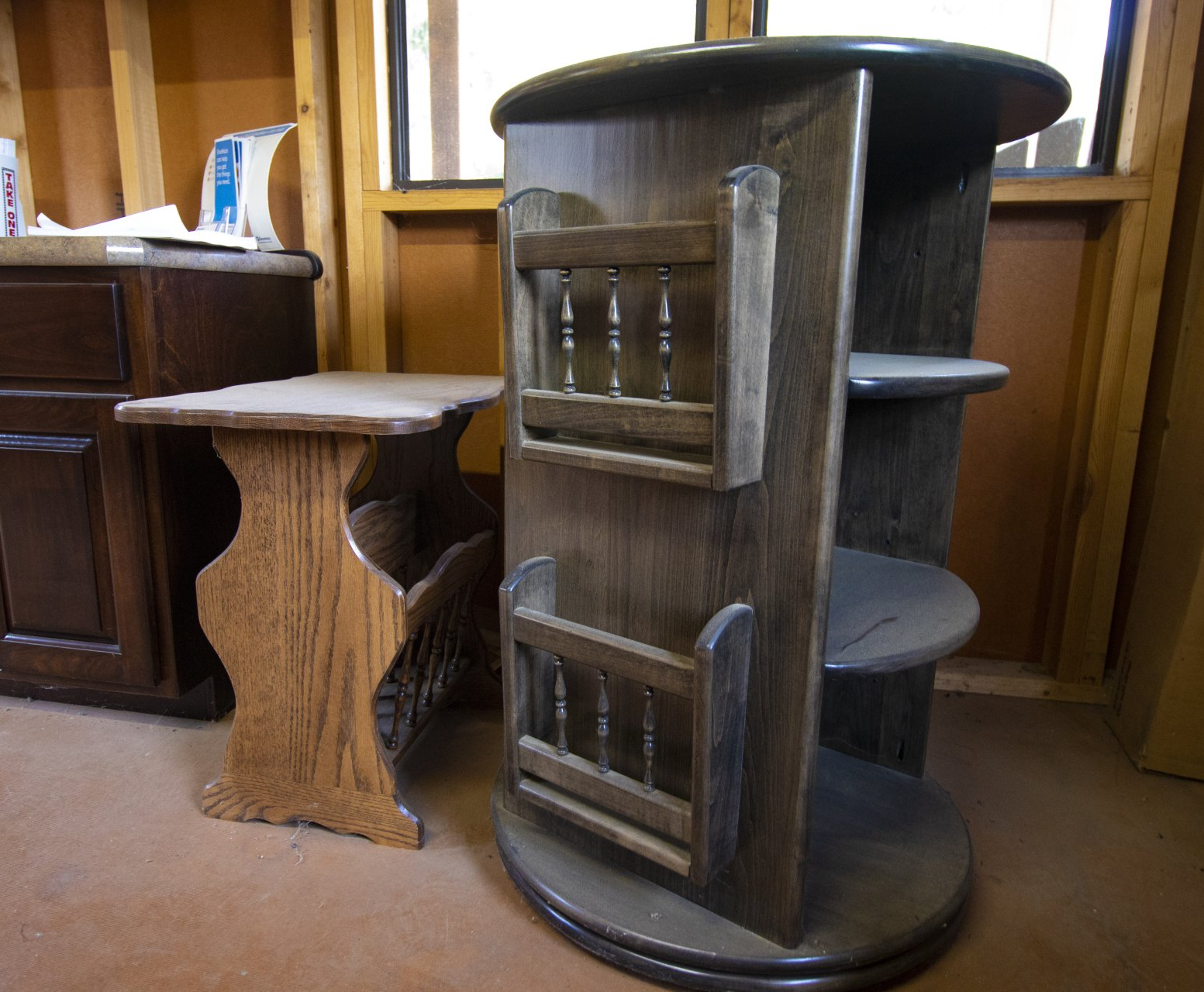 Wooden furniture: side table, magazine rack, and display stand. Brown interior setting.