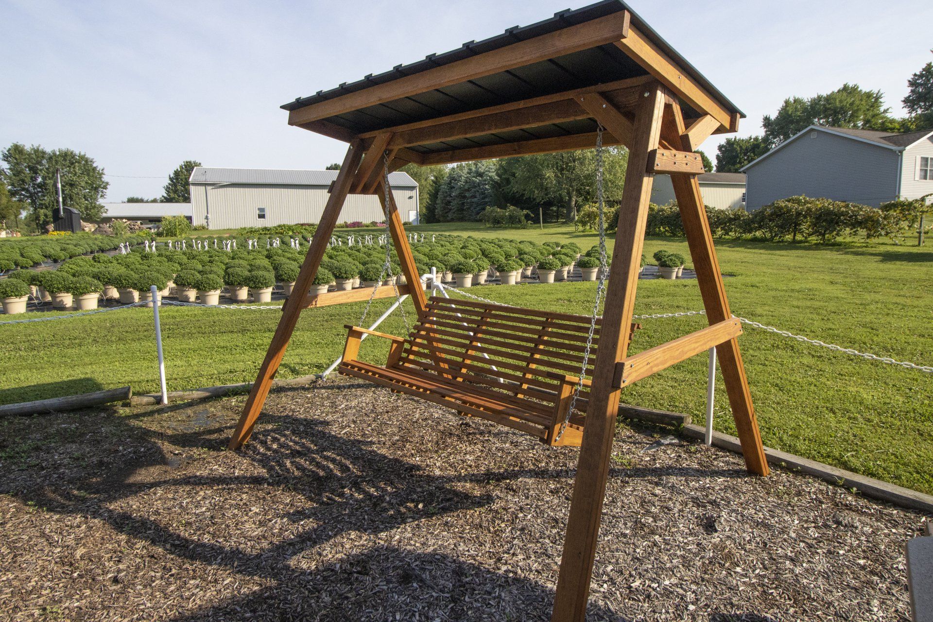 Wooden swing with roof in a grassy field.