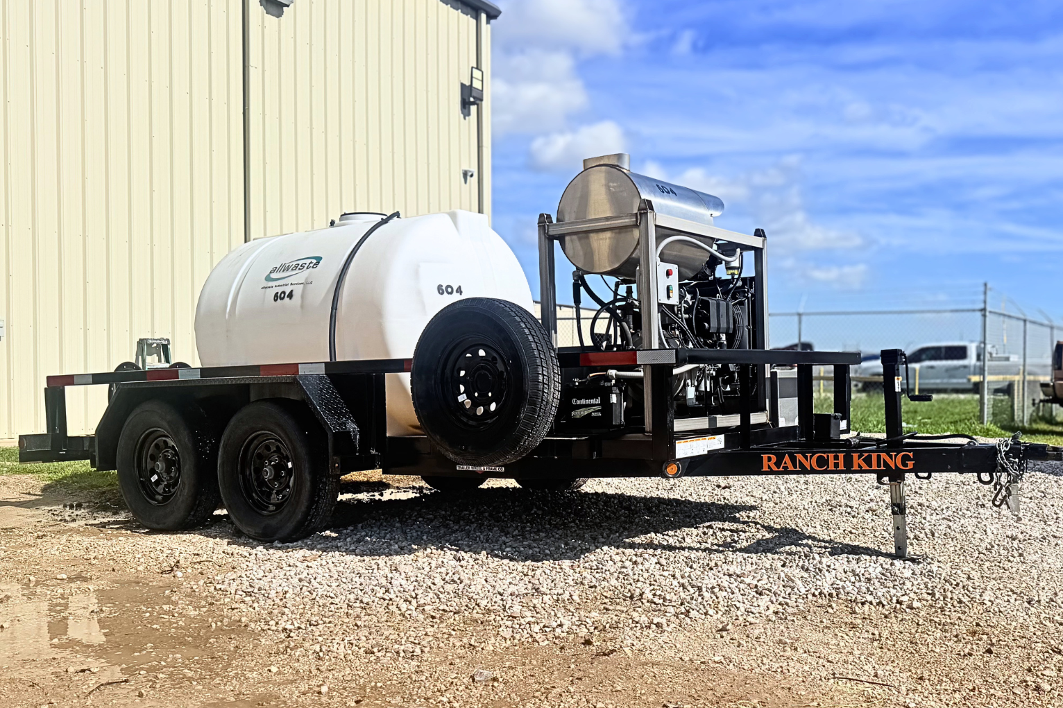 White water tanker trailer beside industrial equipment on gravel under a blue sky