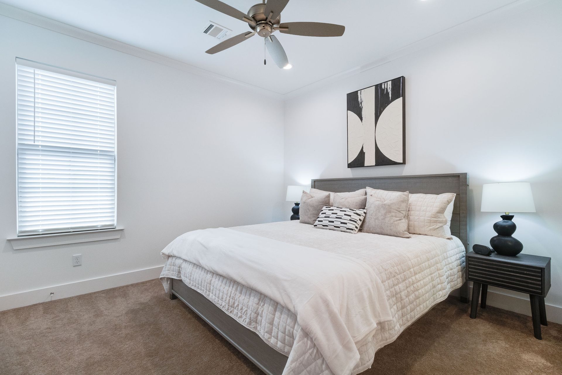 A bedroom with a large bed and a ceiling fan.