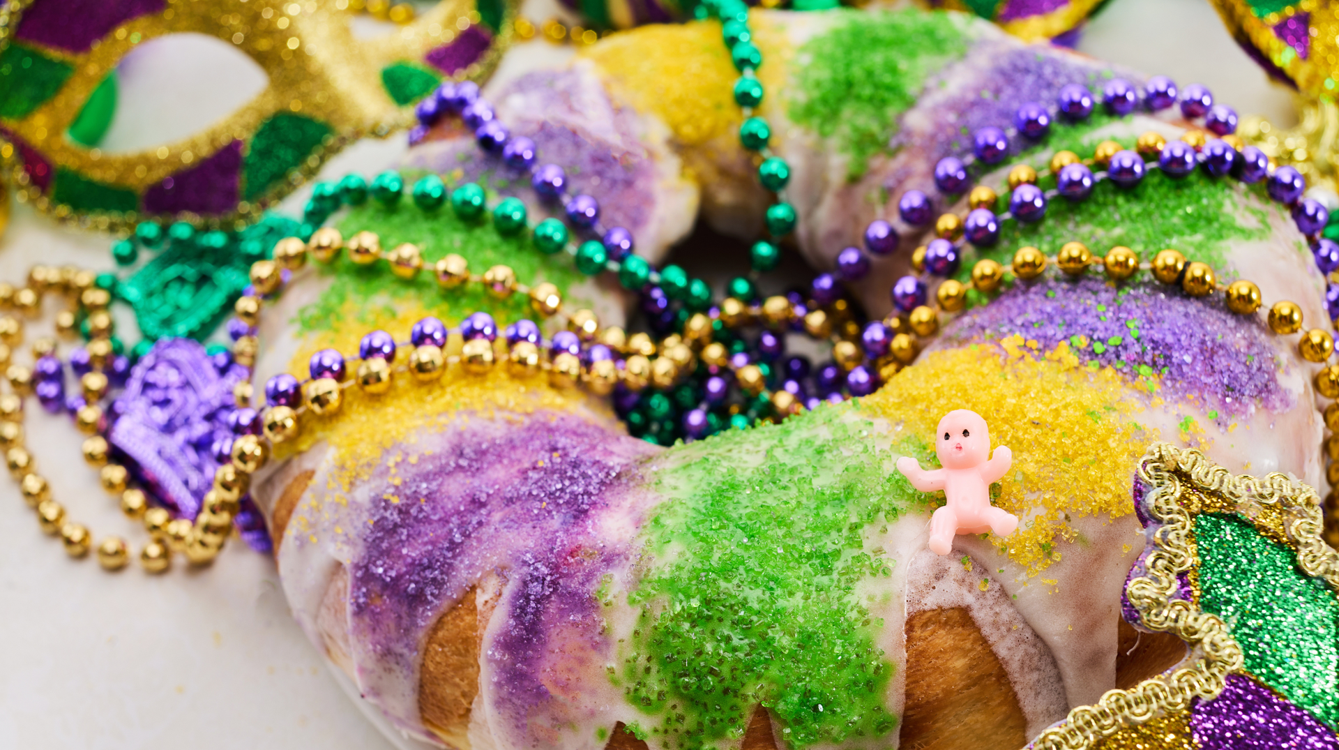 Mardi Gras king cake promoting code MARDIGRAS26 for 15% off a Carnival season stay in Lafayette.