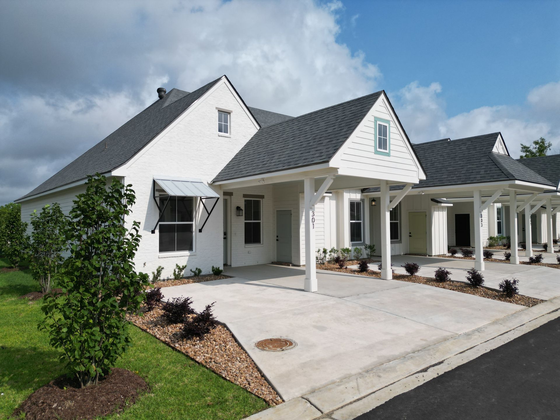 A white house with a black roof and a driveway