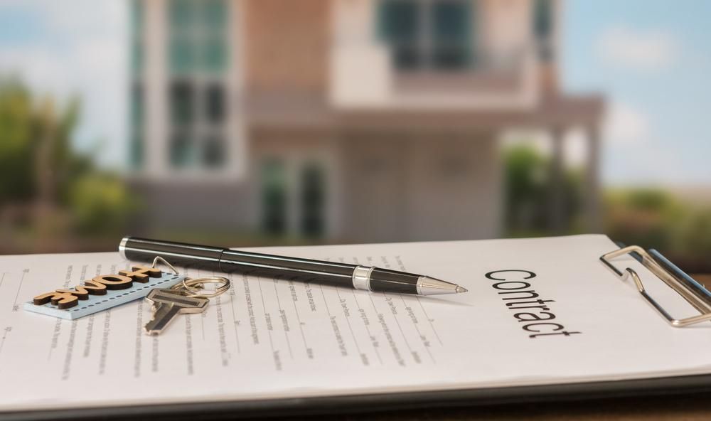 A Clipboard with A Pen and Keys on It in Front of A House — Jarrett Lawrie Conveyancing in Parap, NT