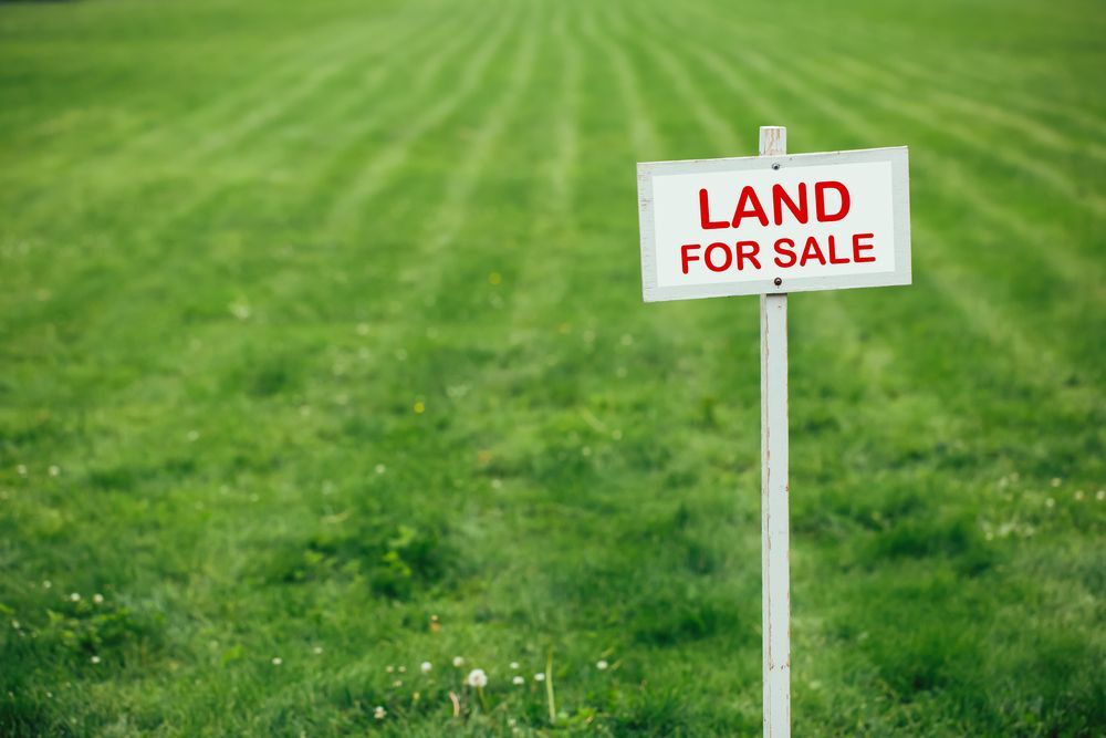 A Land for Sale Sign Is in The Middle of A Lush Green Field — Jarrett Lawrie Conveyancing in Parap, NT