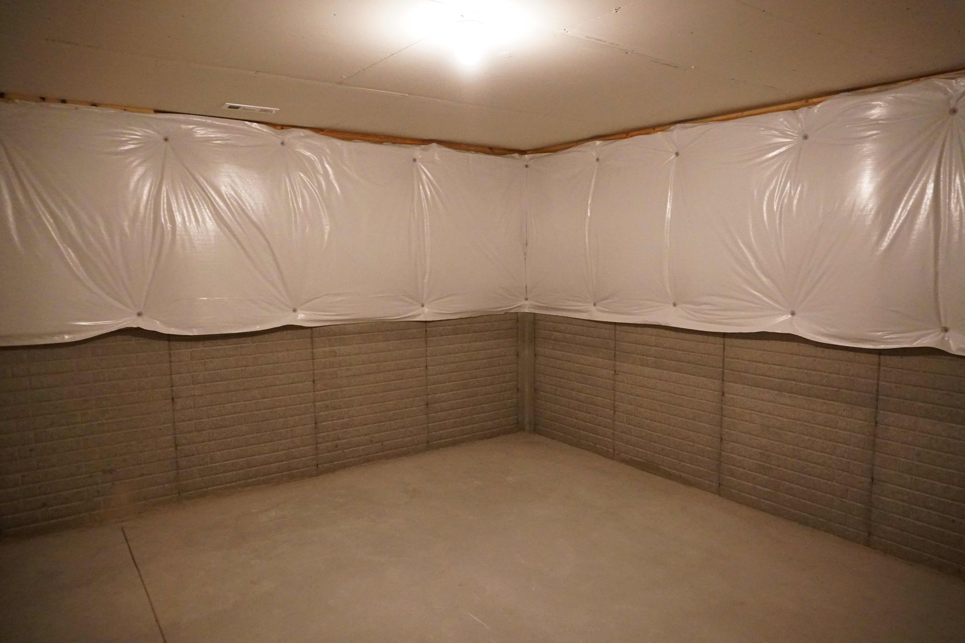 An empty basement with a lot of plastic covering the walls.
