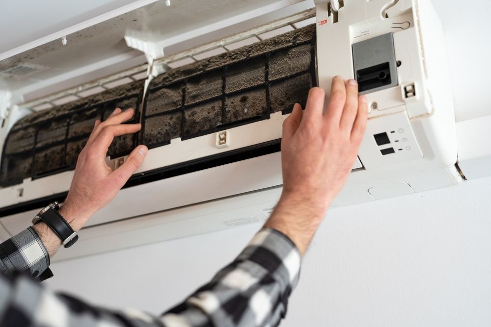 A Person Wearing a Plaid Shirt Opens the Front Panel of Air Conditioner — Confac Energy Services in Lenah Valley, TAS