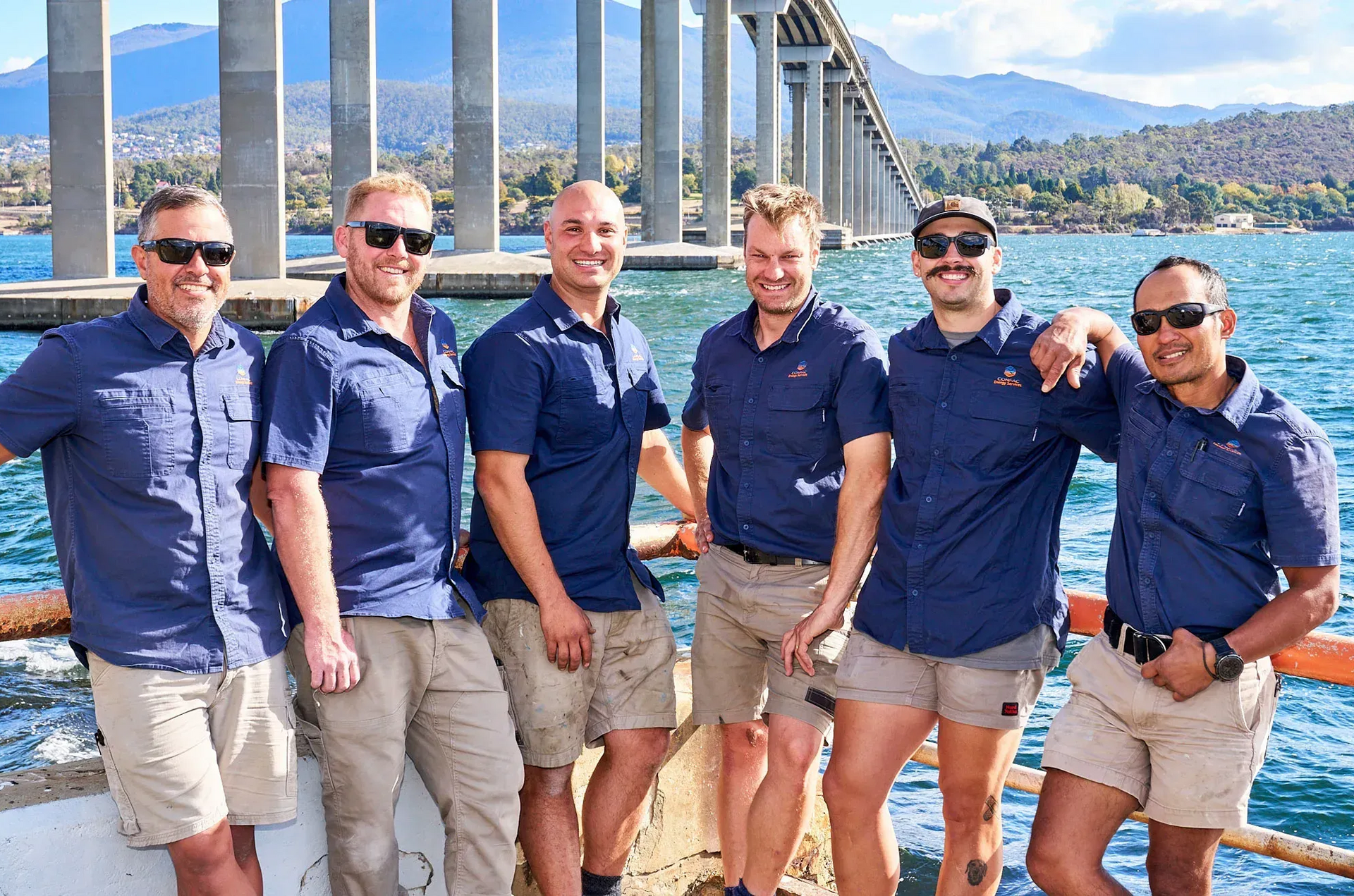 Six People in Matching Navy Shirts and Khaki Shorts Stand Together — Confac Energy Services In Lenah Valley, TAS