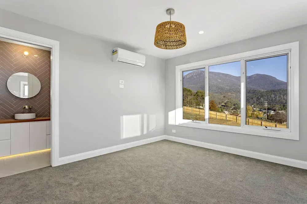 A Bedroom With Grey Walls, Carpet, a Light Fixture, a Split-system AC — Confac Energy Services in Lenah Valley, TAS
