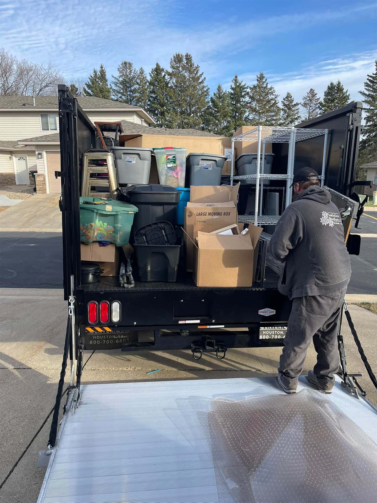 Man loading a packed truck bed with boxes, bins, and shelving
