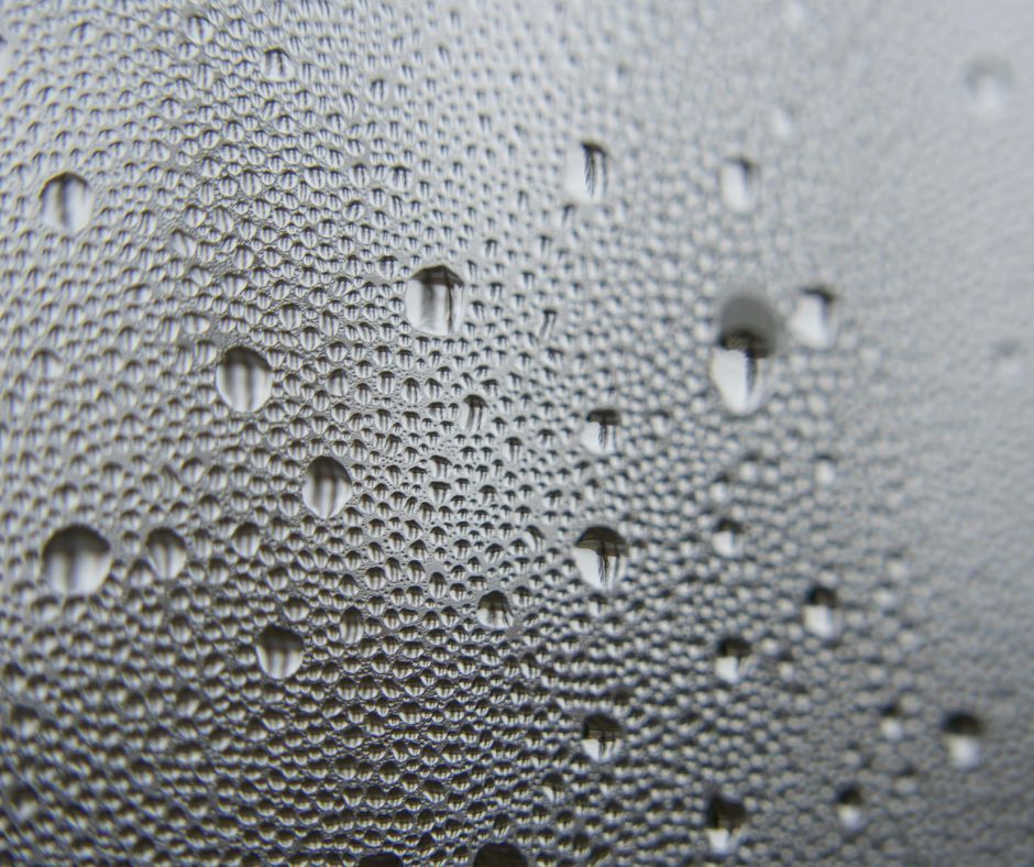 Close-up of water droplets beading on a gray textured surface.