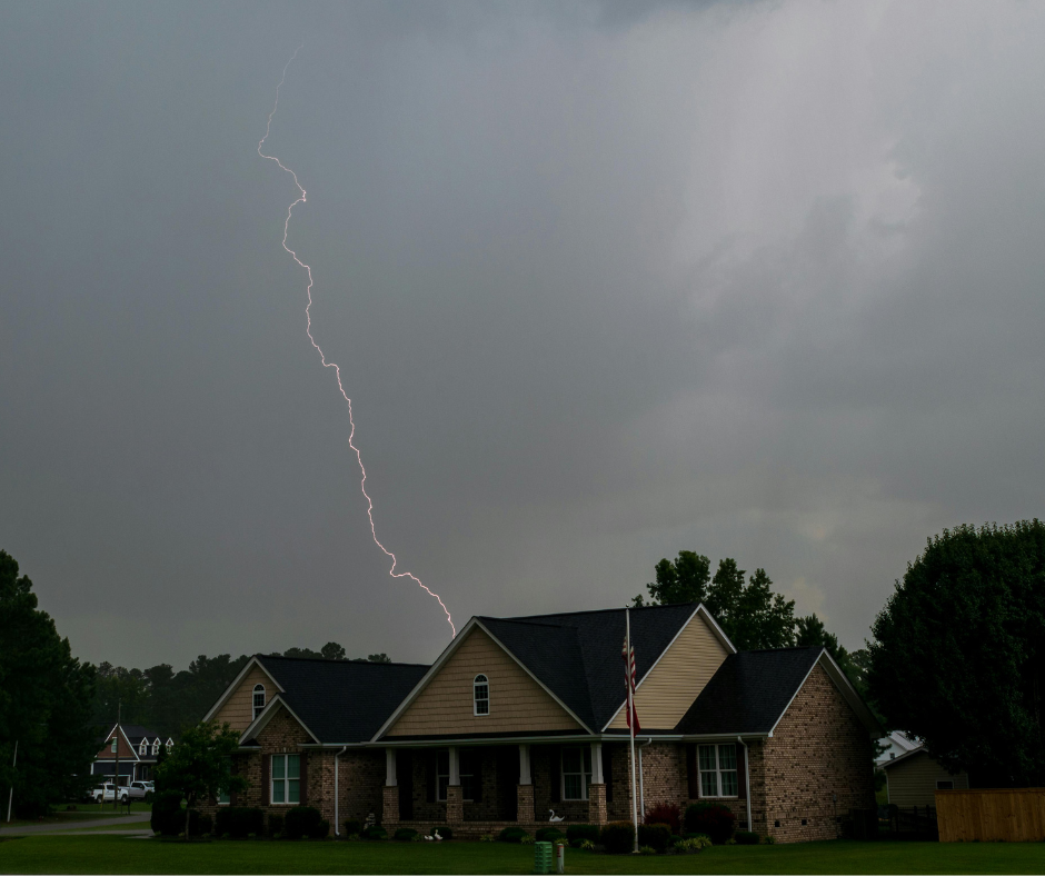 Lightning striking near a suburban house under dark storm clouds