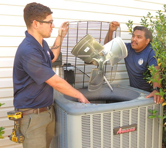 Two CTC technicians performing maintenance on a condenser