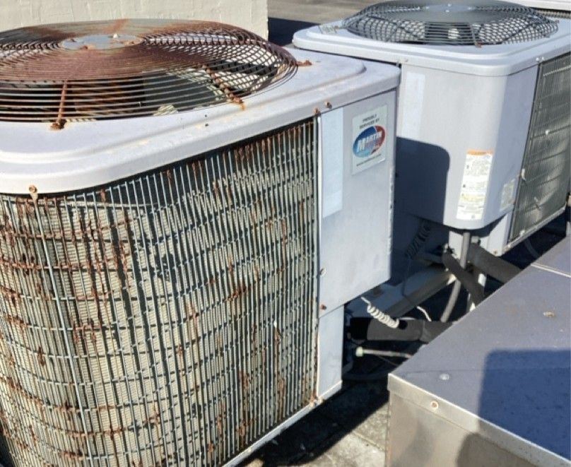 A rusty air conditioner is sitting on top of a concrete block.