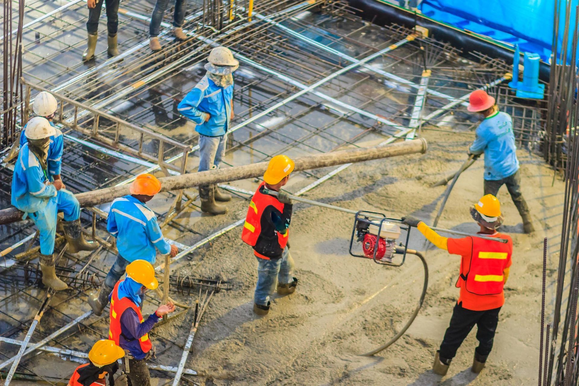 Construction workers pouring concrete on a building foundation.