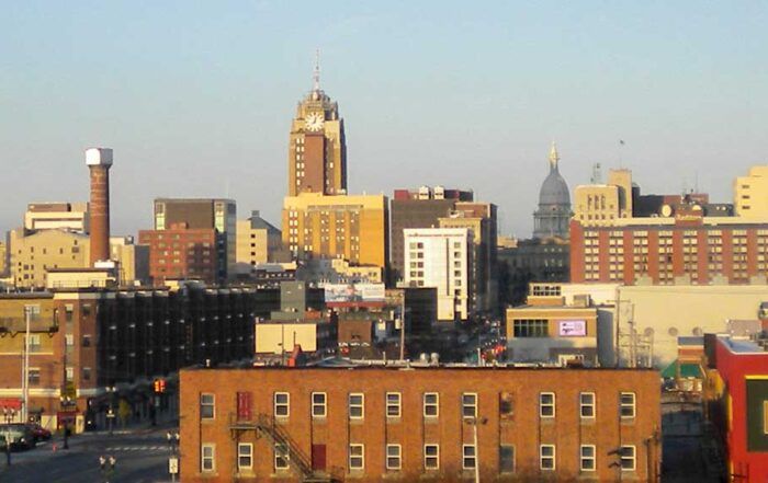 Skyline of Lansing, Michigan, featuring downtown buildings, a clock tower, and the state capitol dome.
