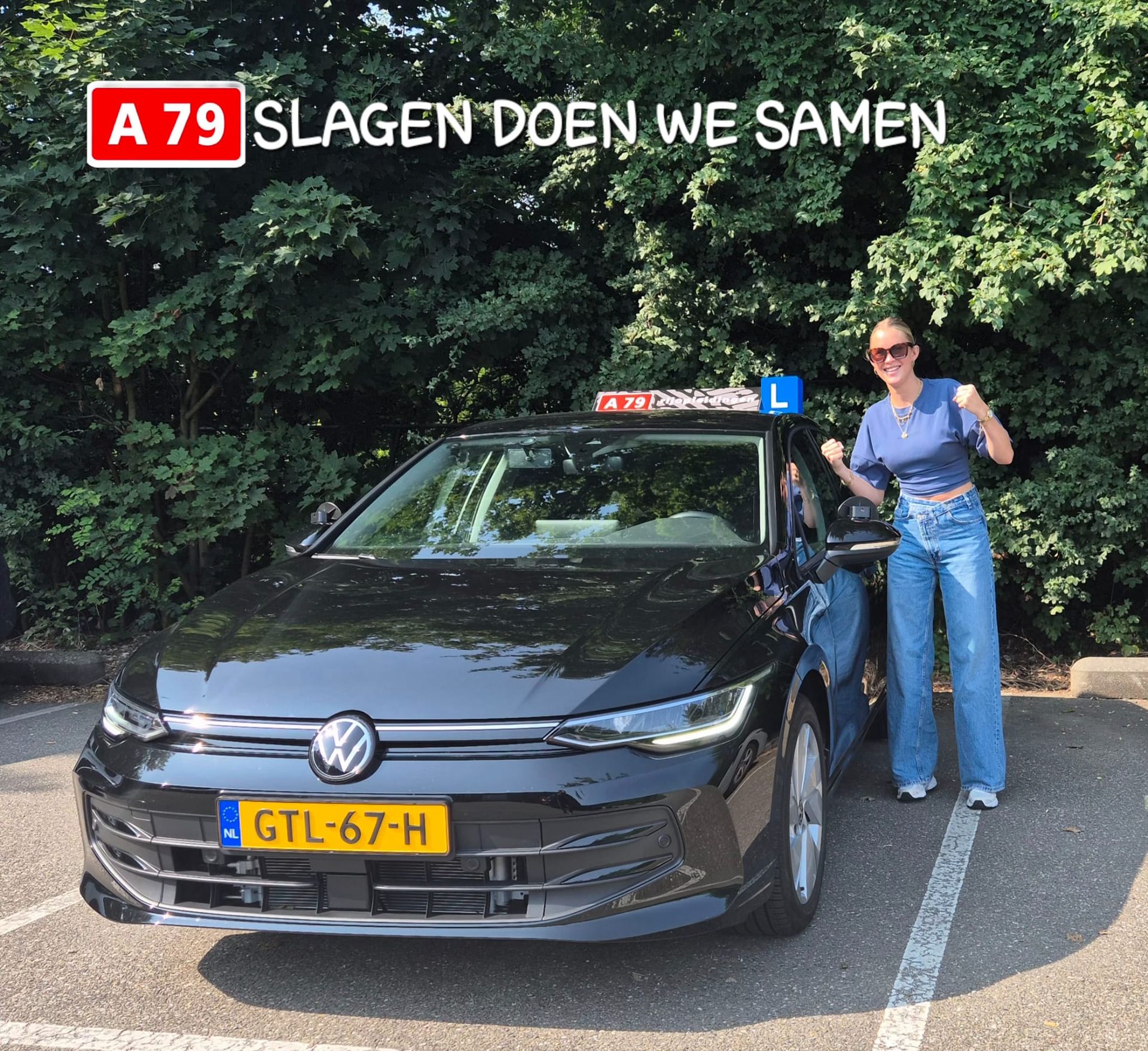 Een vrouw glimlacht naast een zwarte Volkswagen lesauto. Op een bord staat: 