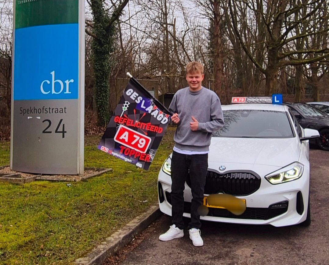 Man met vlag naast auto bij rijexamenlokaal.