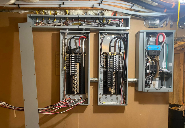 Open electrical breaker panel with exposed wiring and circuit breakers in a utility room