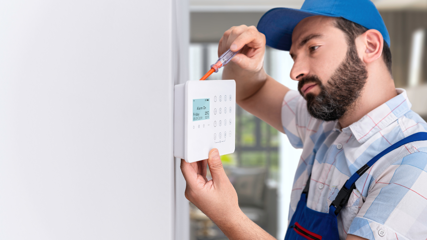 A person is installing a smoke detector on the ceiling.