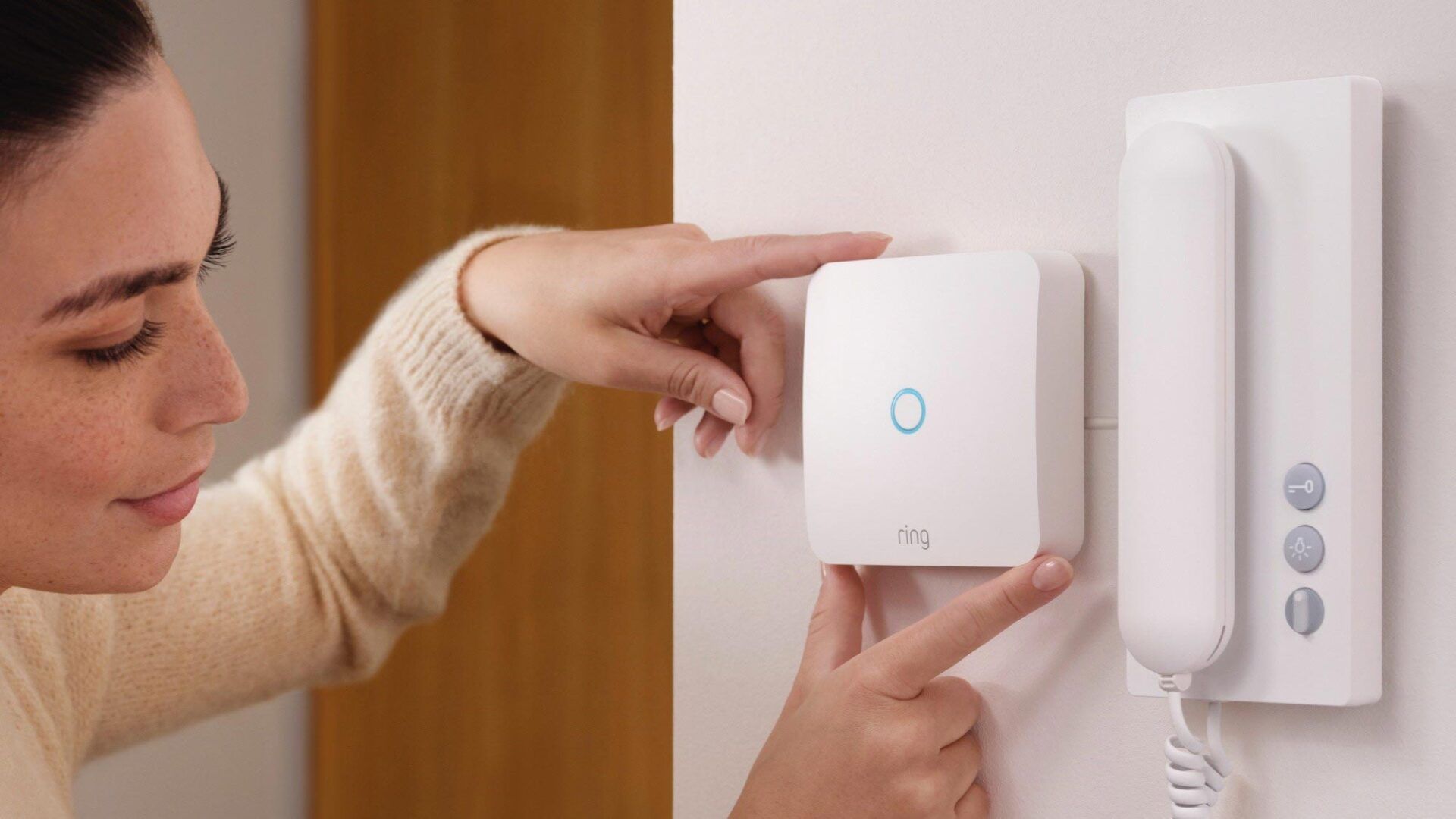 A woman is plugging a device into a doorbell.