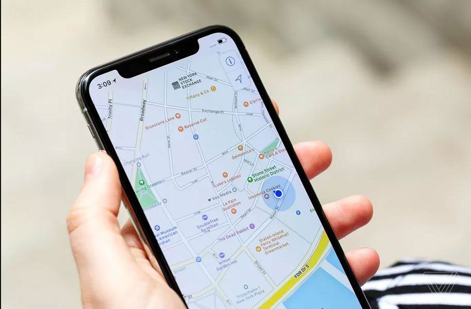 A person is holding a cell phone with a map on the screen.
