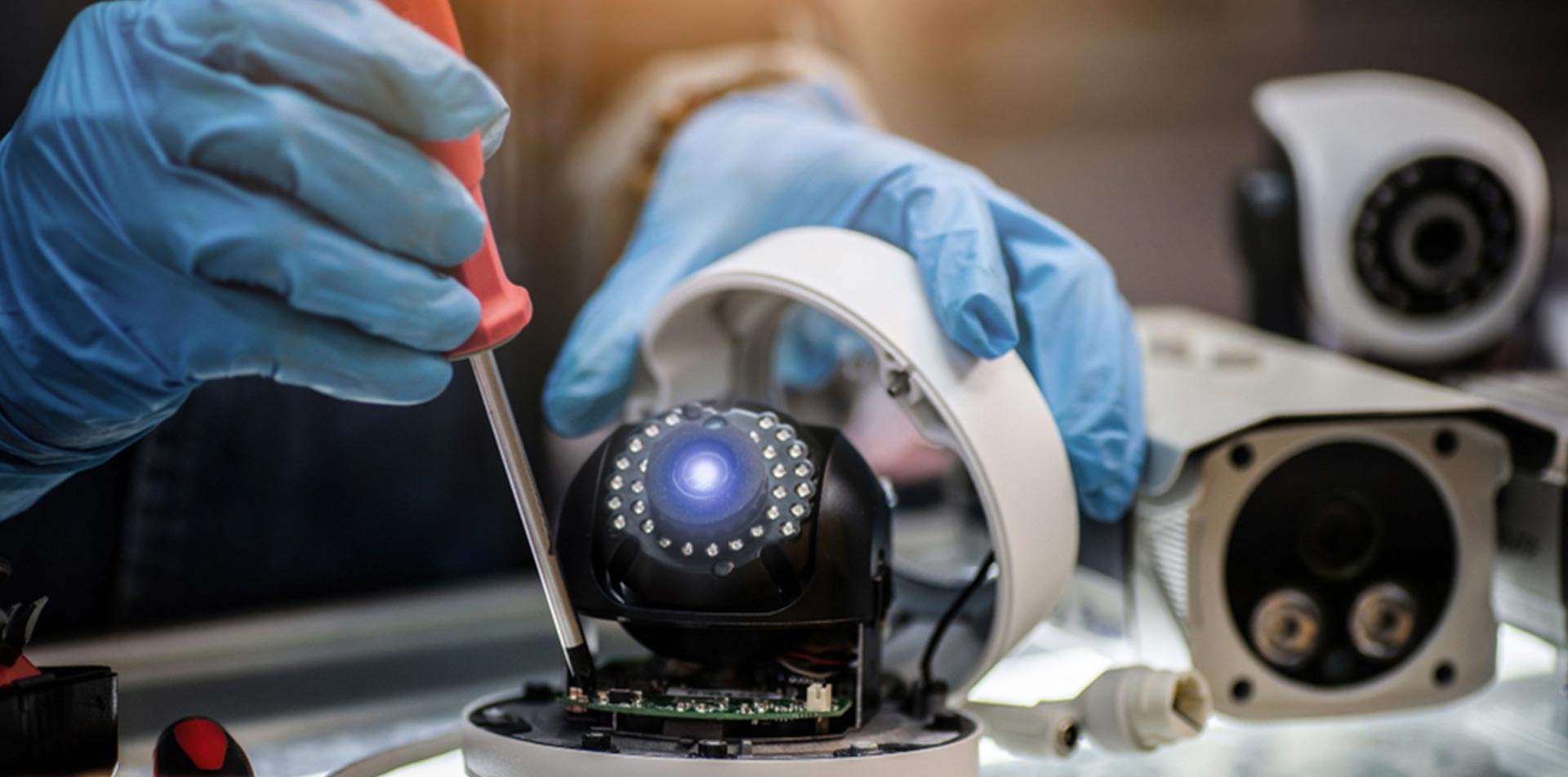 A person is fixing a security camera with a screwdriver.