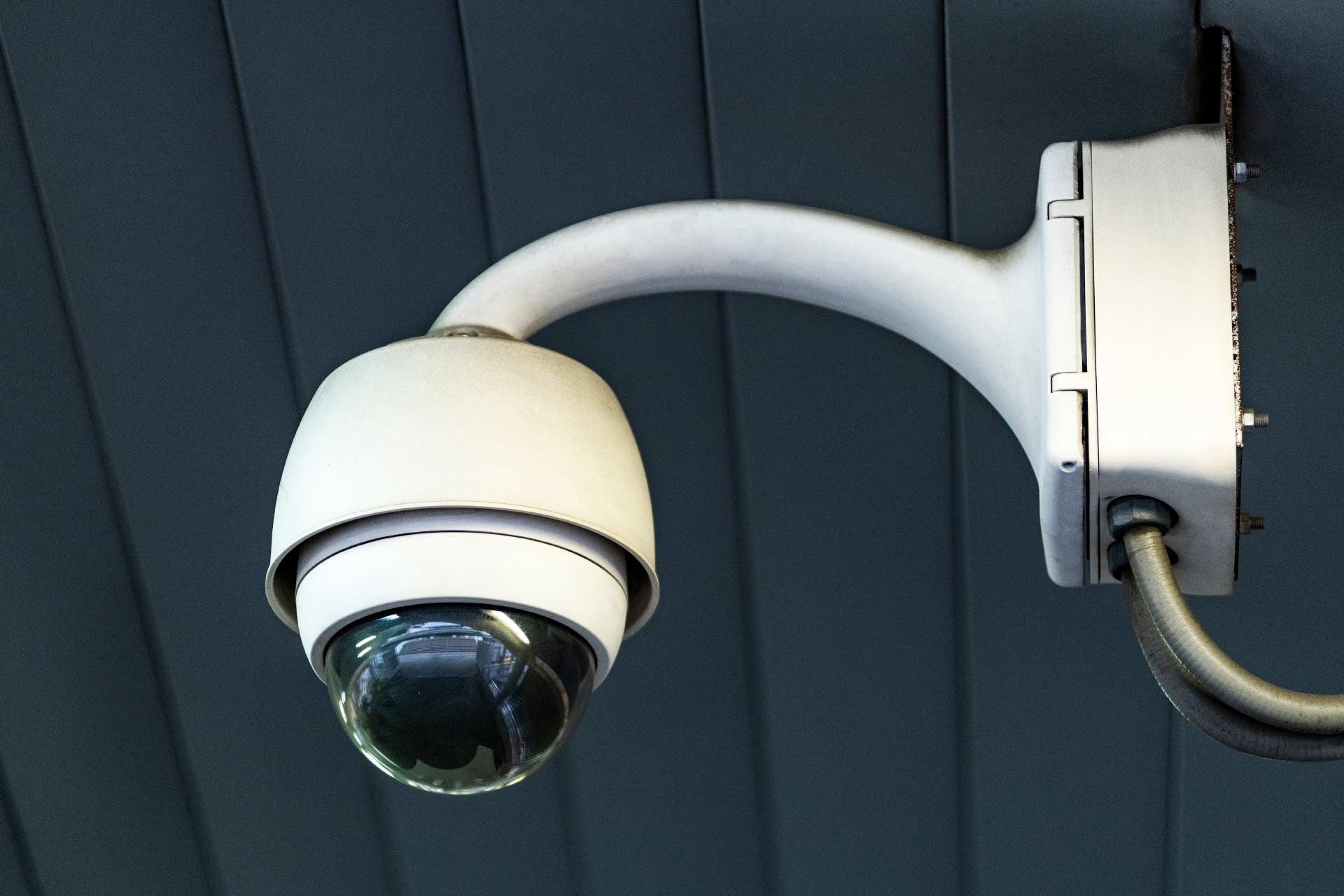 Security System Repair A security camera mounted to a wall with a cable attached to it