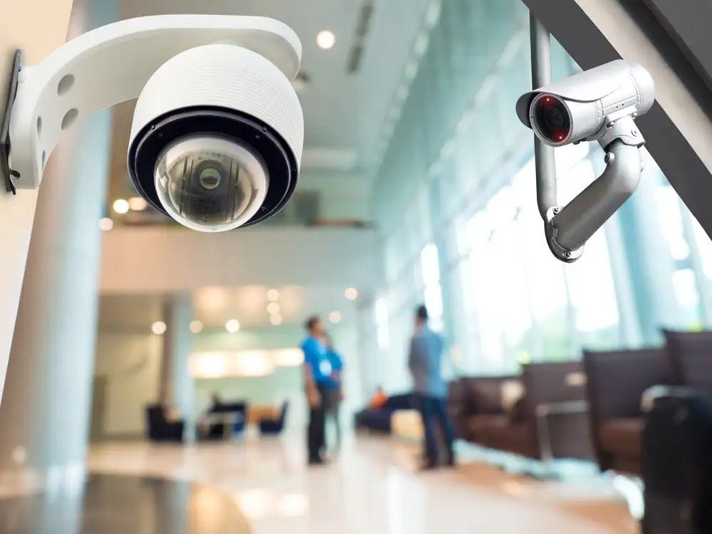 A security camera is hanging from a pole in a lobby.