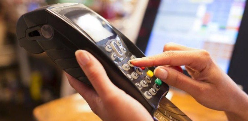 A person is holding a credit card and using a credit card machine.