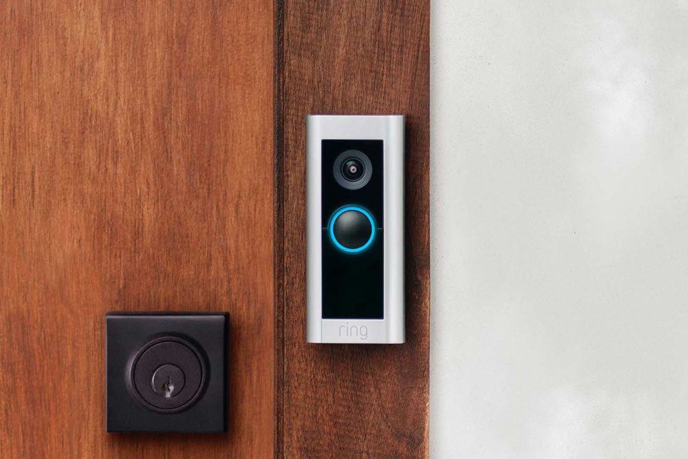 A doorbell is sitting on a wooden door next to a lock.