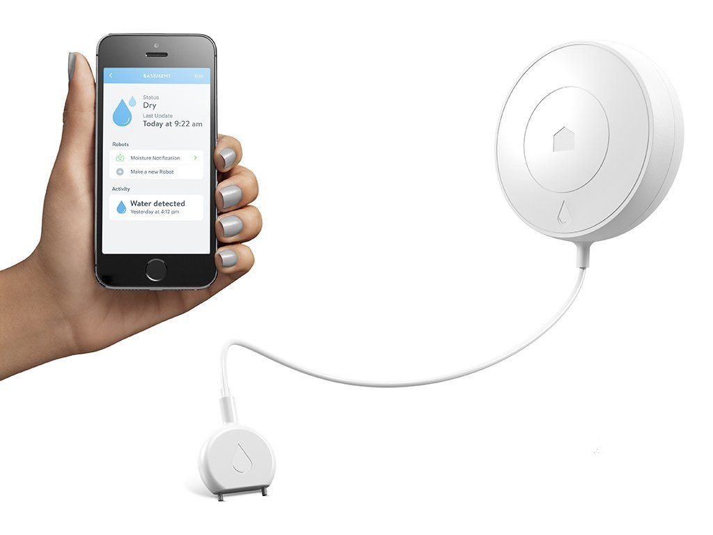 A person is holding a cell phone next to a water sensor.