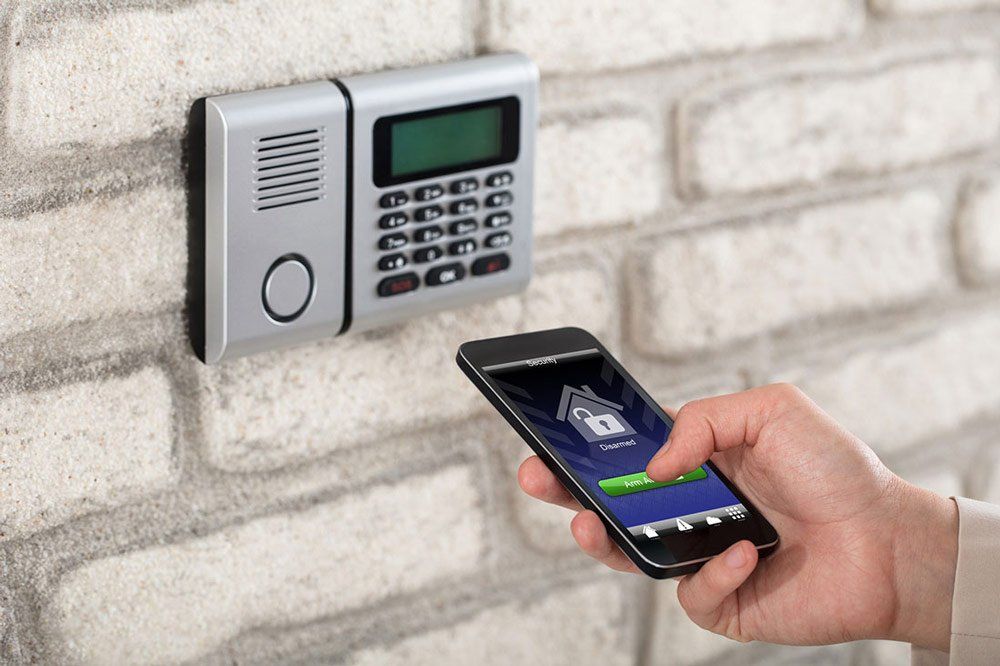 Security System Repair A person is using a smart phone to control a security system.