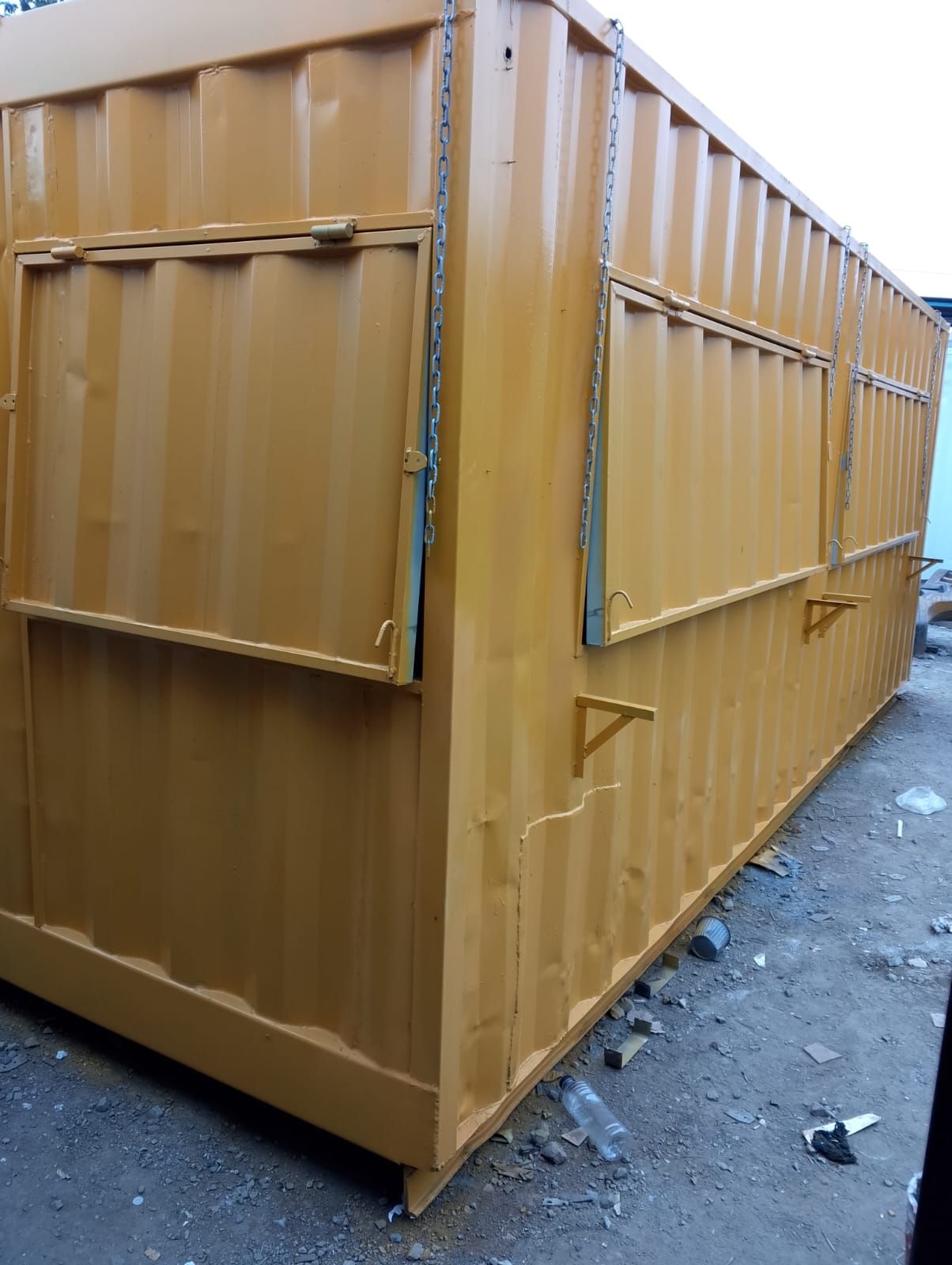 Un contenedor de transporte de metal corrugado amarillo, modificado con dos ventanas de servicio plegables
