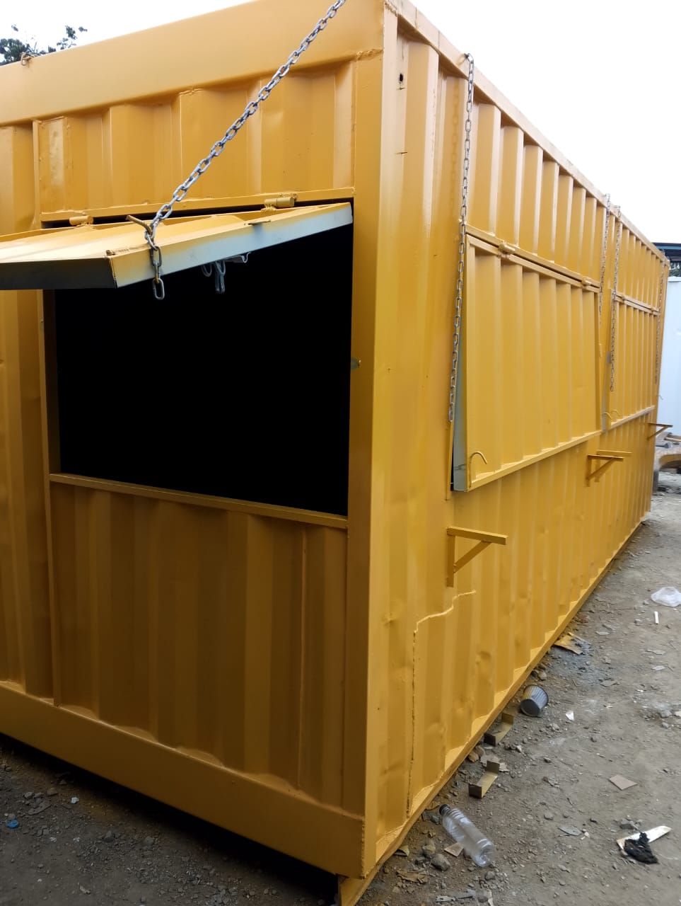 Un contenedor de transporte de color amarillo brillante convertido en un pequeño quiosco con ventanas